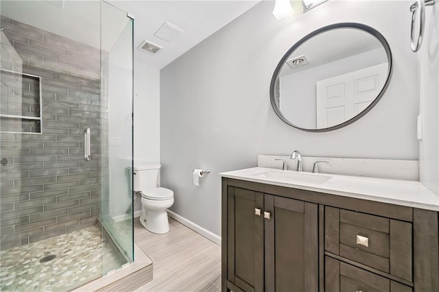 bathroom featuring visible vents, toilet, a stall shower, vanity, and baseboards