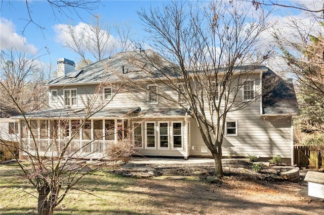 back of property with a chimney and fence