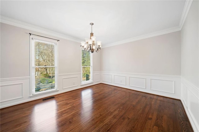 empty room featuring crown molding, wood finished floors, visible vents, and an inviting chandelier