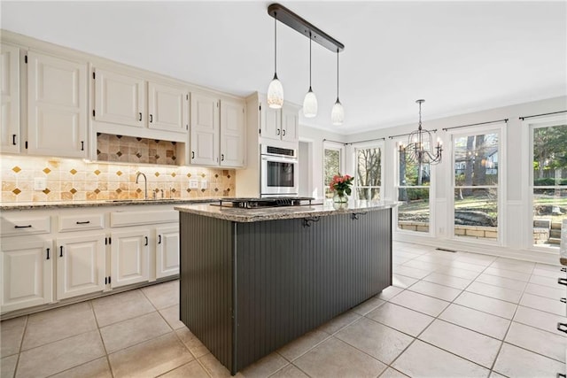 kitchen with tasteful backsplash, appliances with stainless steel finishes, light tile patterned flooring, a sink, and light stone countertops