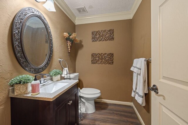 half bathroom with ornamental molding, a textured ceiling, vanity, and wood finished floors