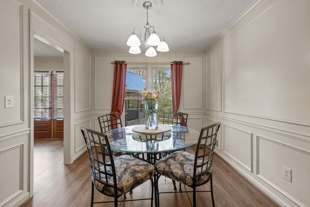 dining area with a notable chandelier, ornamental molding, and a decorative wall