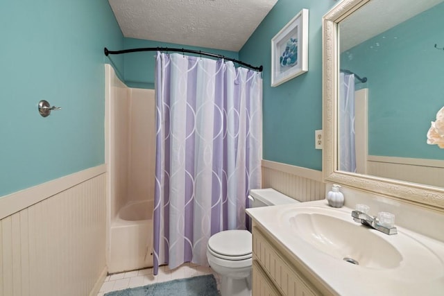 bathroom featuring a wainscoted wall, a textured ceiling, toilet, and vanity