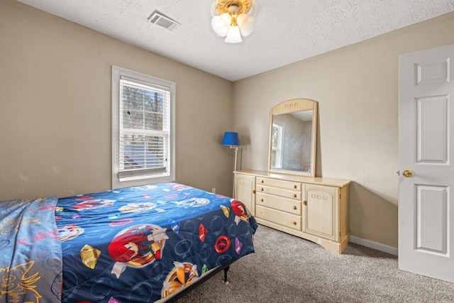 bedroom with baseboards, visible vents, light carpet, and a textured ceiling