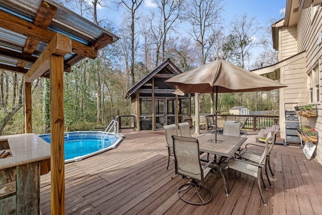 wooden deck with a sunroom, an outdoor pool, and outdoor dining area