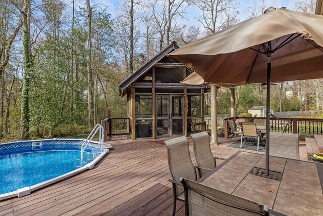 outdoor pool with a deck, outdoor dining area, and a sunroom