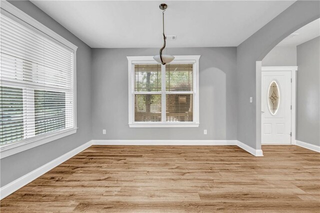 1714 Boulder Walk Ln SE, Atlanta, GA 30316 - unfurnished dining area with plenty of natural light, baseboards, light wood finished floors, and arched walkways