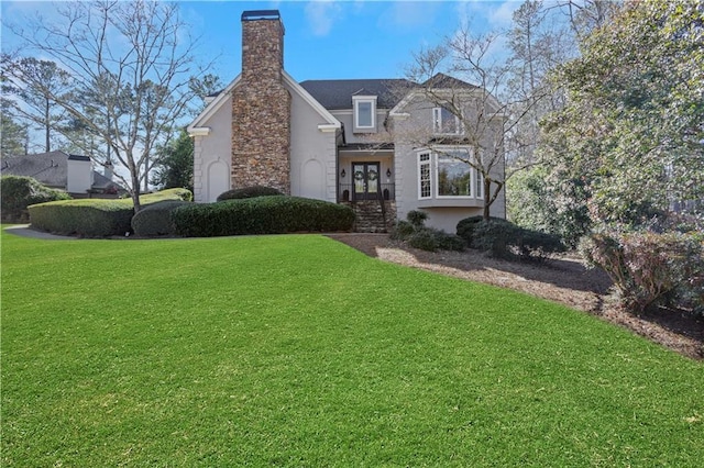 view of front of home featuring french doors, a chimney, a front lawn, and stucco siding