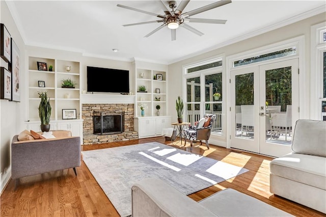 living area with plenty of natural light, french doors, a fireplace, and ornamental molding