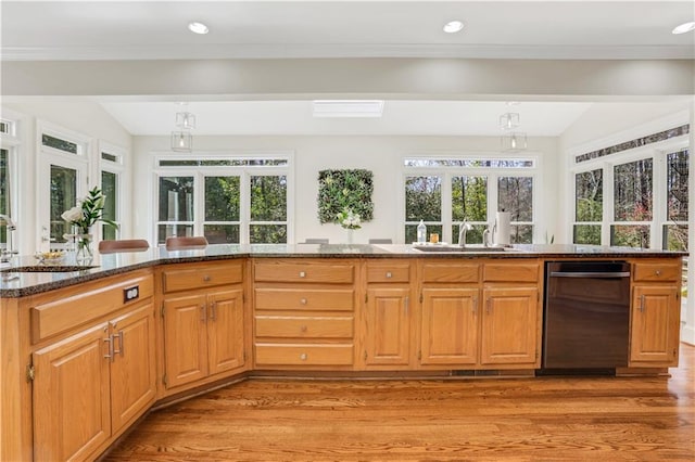 kitchen with dark stone counters, light wood finished floors, a wealth of natural light, and a sink