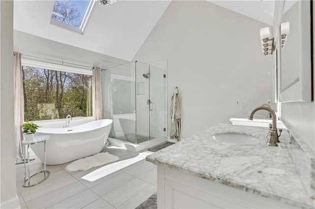 full bathroom featuring a freestanding tub, high vaulted ceiling, a stall shower, a skylight, and vanity