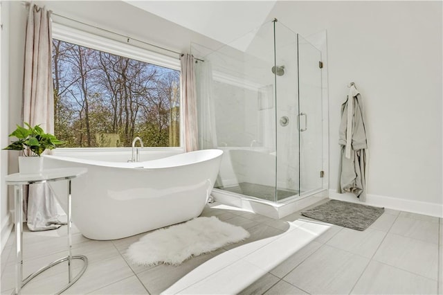 bathroom with tile patterned flooring, baseboards, a marble finish shower, and a freestanding bath