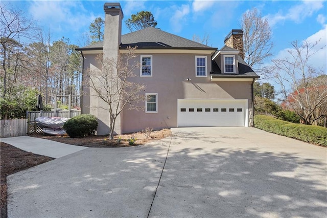 view of side of home with stucco siding, driveway, fence, a garage, and a chimney