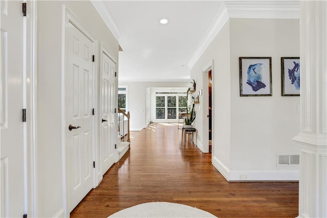 hall with visible vents, baseboards, stairs, ornamental molding, and wood finished floors