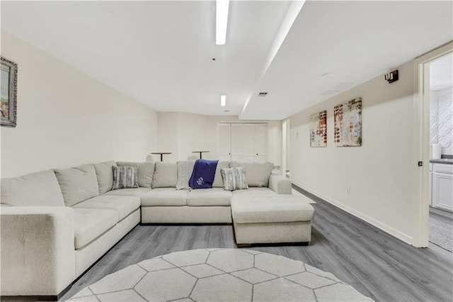 living room featuring visible vents, baseboards, and wood finished floors