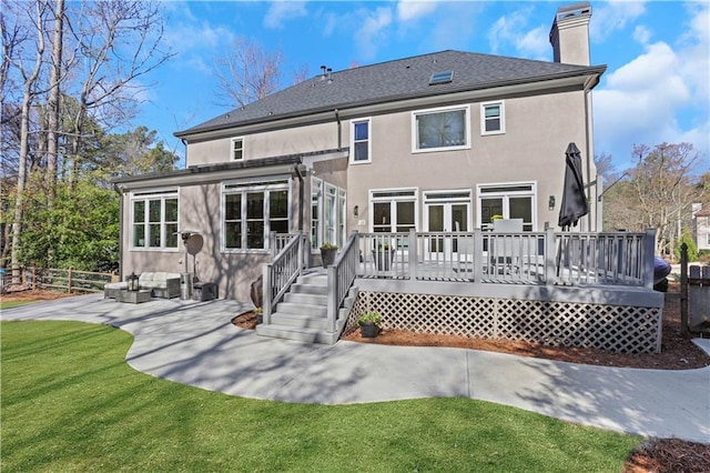 back of house with a wooden deck, stucco siding, a chimney, a yard, and a patio area