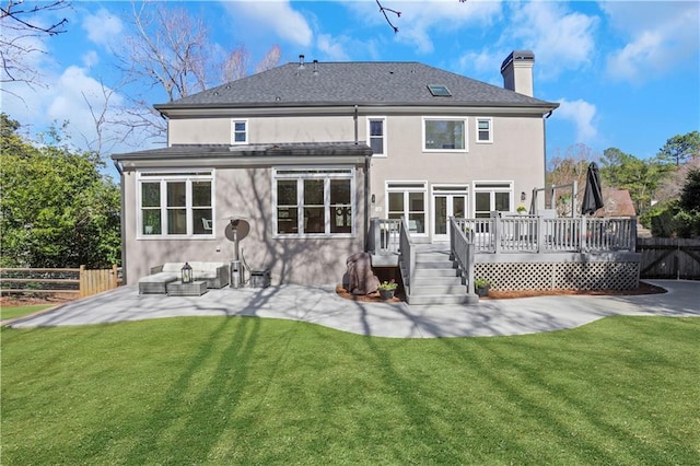 back of property featuring stucco siding, a lawn, a deck, and fence