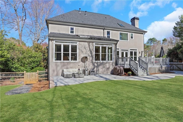 back of house featuring a wooden deck, a patio area, a lawn, and fence