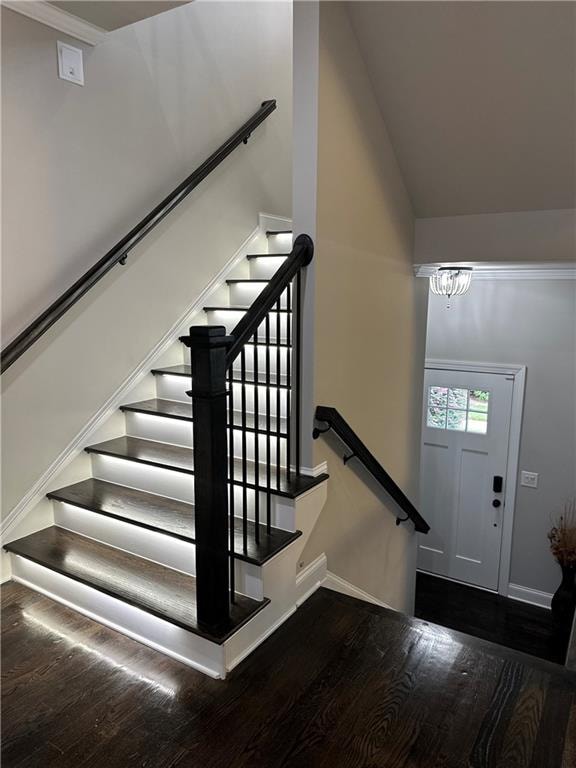 staircase featuring lofted ceiling, a notable chandelier, and hardwood / wood-style flooring