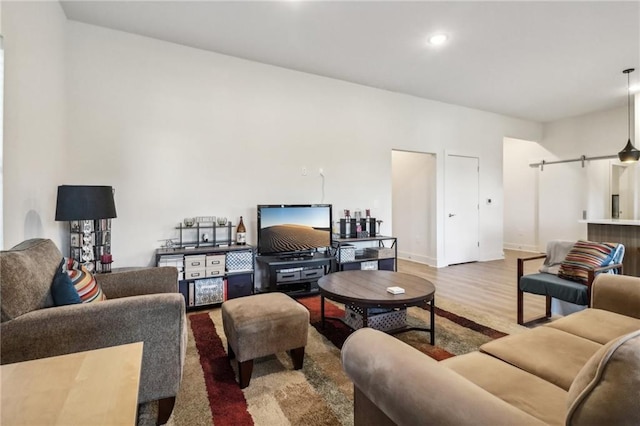 living area with recessed lighting, wood finished floors, baseboards, and a barn door