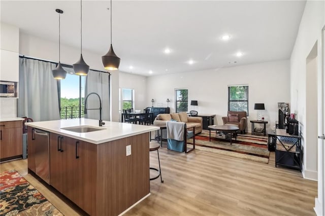 kitchen featuring light countertops, a sink, light wood-style flooring, and a center island with sink