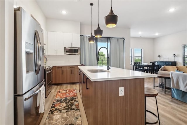 kitchen featuring stainless steel appliances, a sink, light countertops, and light wood-style floors