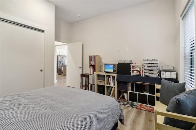 bedroom featuring stainless steel fridge and wood finished floors