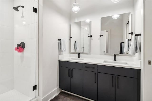 bathroom featuring double vanity, a shower stall, baseboards, and a sink