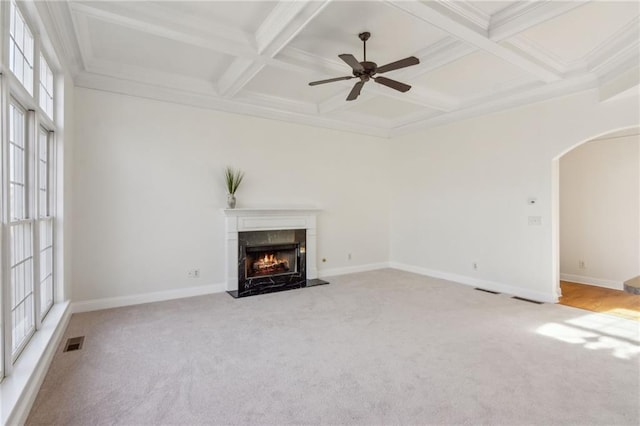 unfurnished living room with coffered ceiling, beam ceiling, a high end fireplace, and light colored carpet