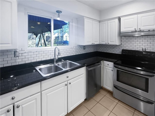 kitchen featuring dark countertops, appliances with stainless steel finishes, white cabinets, a sink, and under cabinet range hood