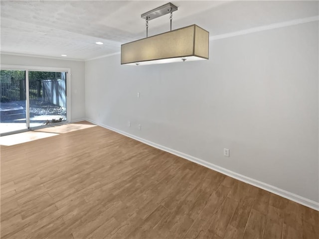 empty room with recessed lighting, crown molding, baseboards, and wood finished floors