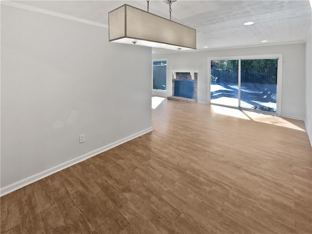 unfurnished living room with baseboards, ornamental molding, wood finished floors, and recessed lighting