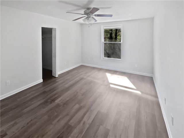 unfurnished room with a ceiling fan, dark wood finished floors, and baseboards