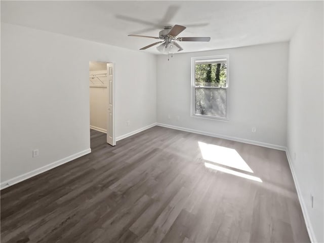 spare room with dark wood-style floors, baseboards, and a ceiling fan