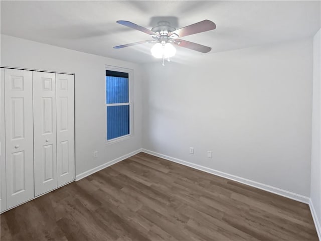 unfurnished bedroom with dark wood-style floors, a closet, ceiling fan, and baseboards