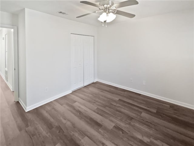 unfurnished bedroom with dark wood-type flooring, a closet, visible vents, and baseboards