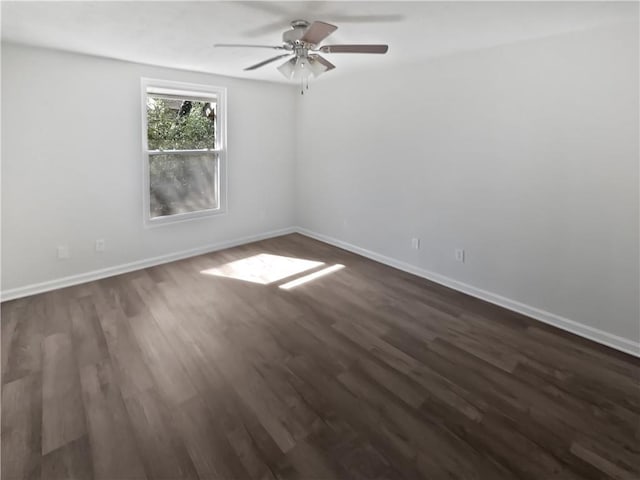 spare room featuring dark wood-style floors, ceiling fan, and baseboards