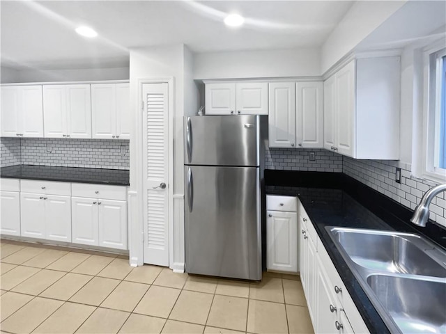 kitchen featuring dark countertops, white cabinets, a sink, and freestanding refrigerator