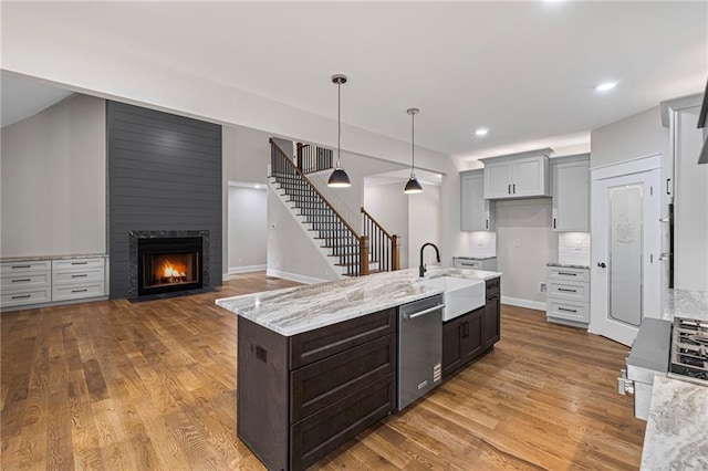 kitchen featuring dishwasher, wood finished floors, a fireplace, and a sink