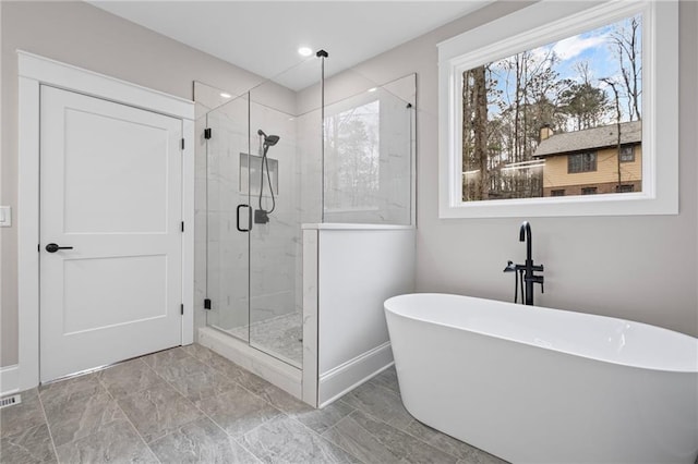 bathroom with a shower stall and a freestanding bath