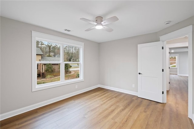 spare room with a wealth of natural light, baseboards, ceiling fan, and wood finished floors