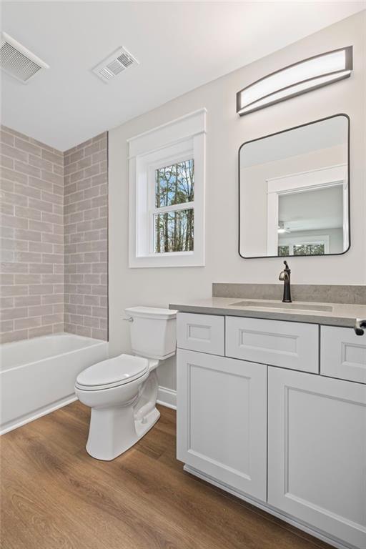 full bath with visible vents, toilet, and wood finished floors