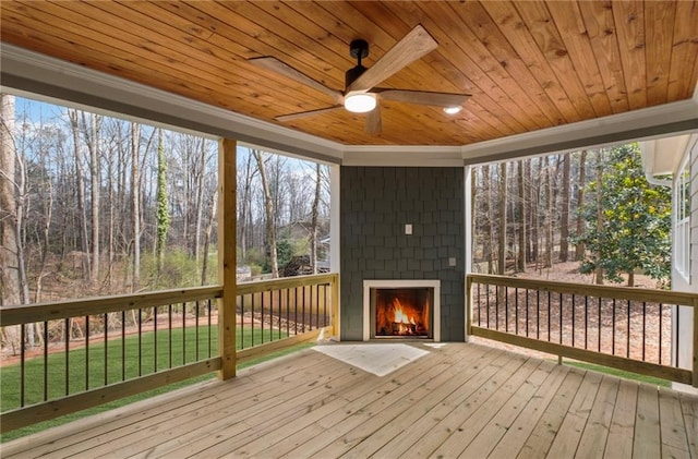 wooden terrace with a ceiling fan and an outdoor brick fireplace