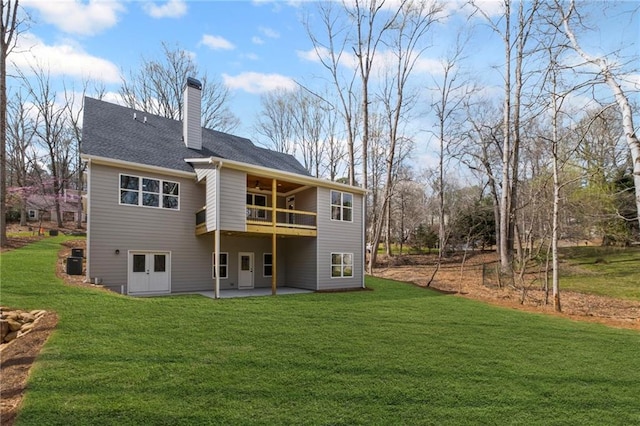 back of house with a patio, a yard, roof with shingles, central AC unit, and a chimney