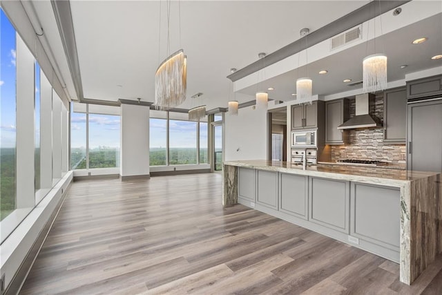 3630 Peachtree Rd NE Unit 2207, Atlanta, GA 30326 - kitchen featuring wall chimney exhaust hood, stainless steel appliances, decorative backsplash, light wood-style floors, and recessed lighting