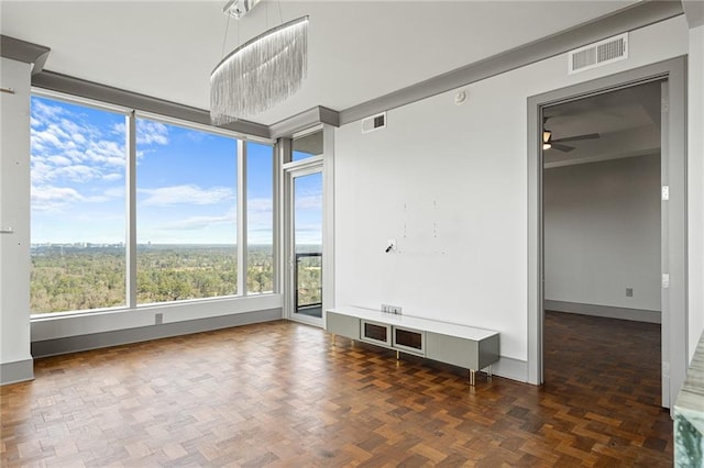 spare room with dark parquet flooring and ceiling fan with notable chandelier