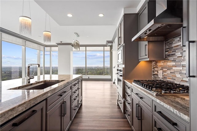 3630 Peachtree Rd NE Unit 2207, Atlanta, GA 30326 - kitchen featuring wall chimney exhaust hood, appliances with stainless steel finishes, a sink, backsplash, and light stone countertops