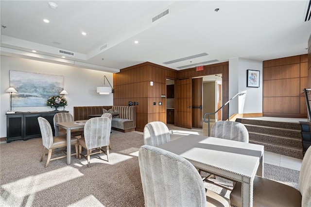 carpeted dining area featuring wooden walls