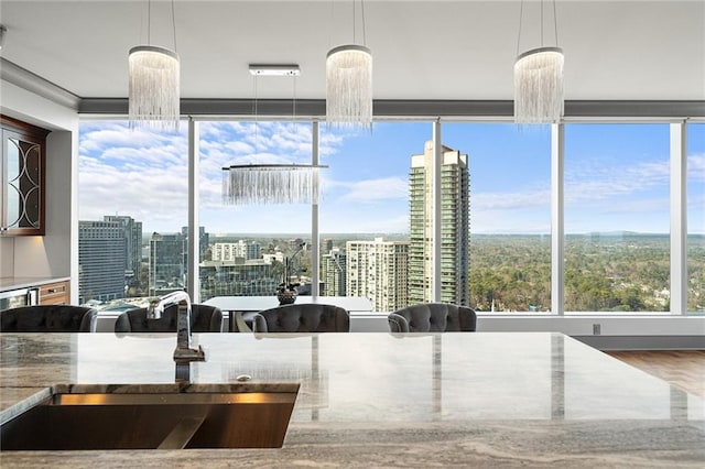 kitchen with light stone counters, hanging light fixtures, and sink