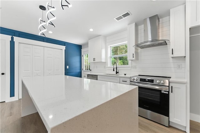 376 Wayside Ln, Dallas, GA 30132 - kitchen featuring wall chimney exhaust hood, stainless steel appliances, light wood-type flooring, decorative backsplash, and white cabinets